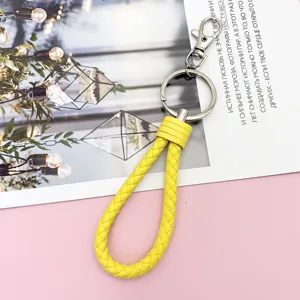 Detailed view of yellow braided leather keychain strap with metal hardware, close-up presentation.