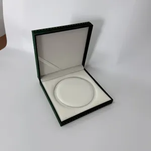 Caja de joyería de terciopelo verde oscuro, estuche cuadrado con borde dorado y interior.