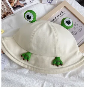 Close-up of beige canvas bucket hat featuring cute 3D frog eyes and embroidered foot details.