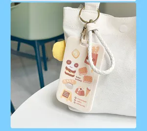 Close-up detail of cute cartoon bread card holder with white braided keychain strap.