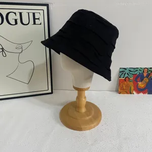 Black pleated bucket hat detail view, breathable summer sun hat showing texture and style.