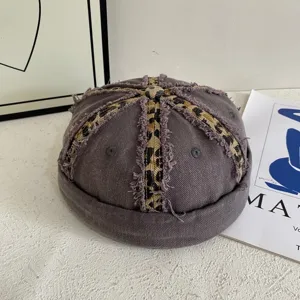 Detailed view of vintage washed patchwork docker cap with stylish leopard print trim and frayed edges.