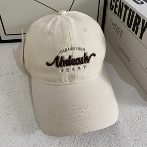 Primer plano detallado de gorra de béisbol de algodón beige con elegante bordado de letras.