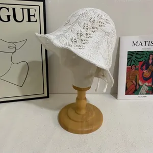 Close-up detail of white hollow knitted bucket hat with delicate wheat pattern and ties for summer.