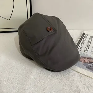 Detailansicht einer dunkelgrauen Retro-Schiebermütze für Damen mit schickem Holzzapfen-Akzent.