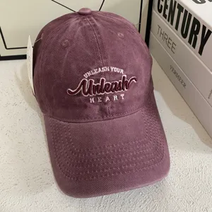 Vista detallada de gorra de béisbol de pana morada con bordado frontal y ala ancha.