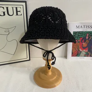 Detailed view of the black crochet bucket hat, featuring a hollow knit design and thin chin straps.