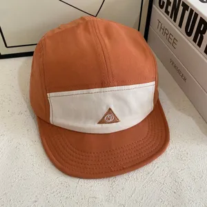Stylische orange-weiße 5-Panel-Camp-Cap mit gesticktem Dreiecks-Logo auf der Vorderseite.