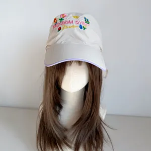 Detail view of beige baseball cap with colorful flower embroidery and wide brim style.