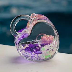 Porte-clés cœur en acrylique transparent avec liquide violet, fleur de lotus et paillettes.