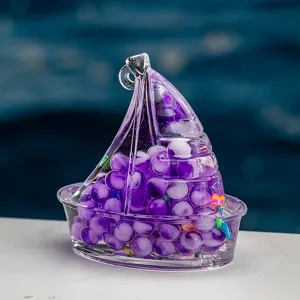 Gros plan sur le pendentif voilier en acrylique transparent rempli de perles violettes.