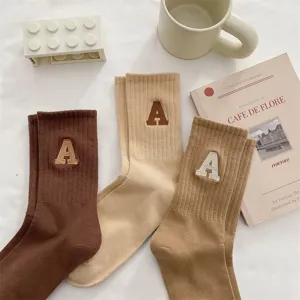 Eleganti calzini a coste in cotone nei toni della terra con ricamo di lettere, comodi e morbidi.