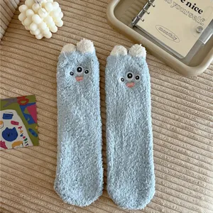 Detail view of fluffy blue fuzzy socks with cute three-eyed monster design for cozy winter home.
