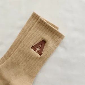 Primo piano dettagliato di calzini a costine kaki in cotone con ricamo della lettera marrone A.
