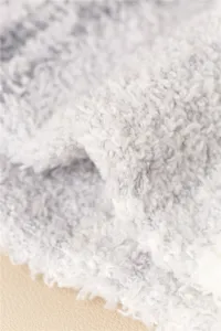 Nahaufnahme der flauschigen Korallenfleece-Textur mit weichem grau-weißen Farbverlauf.