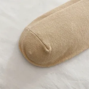 Primo piano della trama del calzino in maglia, tessuto beige morbido e rifinito.