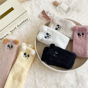 Flauschige Korallenfleece Damen Socken mit Katzenstickerei und Bommeln für warme Füße zu Hause.