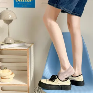 Detail view of women low cut invisible boat socks paired with denim shorts and casual canvas shoes.