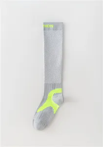 Détail de chaussette de compression sportive grise avec zones de soutien et texte fluo.