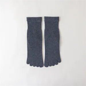 Gros plan sur des chaussettes a cinq orteils en coton gris fonce avec un design mi-haut.