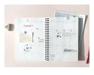 Detailansicht eines Spiral-Planer-Notizbuchs mit Monatskalender-Raster und süßen Dekostickern.
