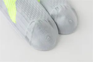 Détail de chaussettes de compression sport grises, tissu tricoté respirant avec accent jaune néon.