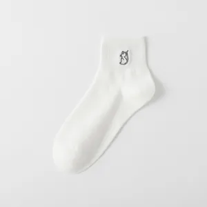 Nahaufnahme von kurzen weißen Baumwollsocken mit einer süßen grauen Katzenstickerei.