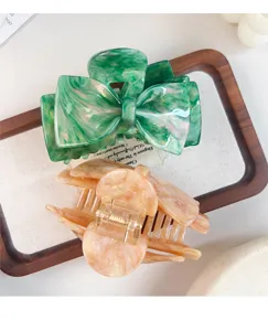Elegant acetate hair claw featuring a green bow and champagne round design, perfect detail view.