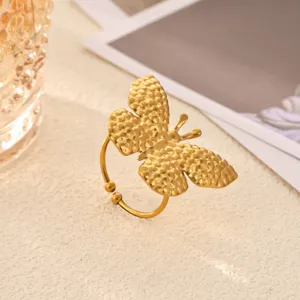 Gold butterfly ring detail shot, minimalist stainless steel fashion jewelry close-up view.