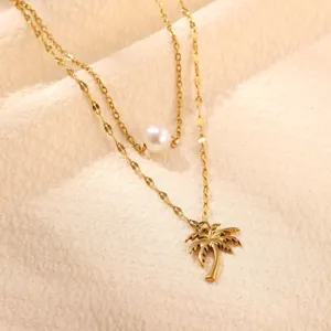 Details der goldenen doppelten Halskette mit Perle und tropischem Palmenanhänger.