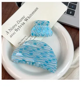 Vista detallada de pinzas para el pelo con diseño azul y blanco en plato de cerámica.