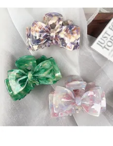 Close-up view of elegant acetate bow hair claws, showcasing vibrant marble patterns and details.
