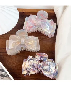 Elegant acetate bow hair claw clip with colorful marble pattern, stylish hair accessory for women.