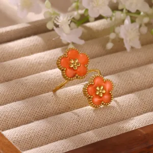 Close-up detail of the orange floral open ring with delicate beaded gold edge on display.