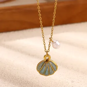 Gold plated shell pendant necklace with pearl detail, close up view of ocean jewelry design.