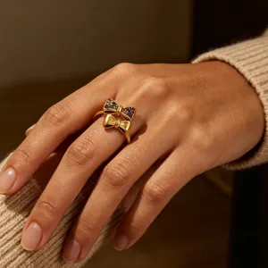 Close-up shot of the double bow ring featuring colorful cubic zirconia and smooth gold metal detail.