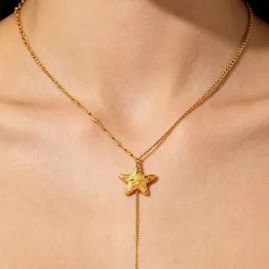 Close-up of a gold Y-chain necklace featuring a delicate starfish pendant worn on the neck.