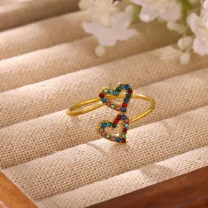 Close-up detail of a stunning gold-plated double heart ring sparkling with colorful multi-gemstones.