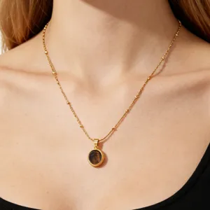 Detailed close-up of a gold-plated titanium steel necklace with a chic oval dark stone pendant.