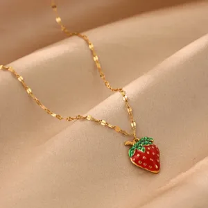 Close-up of a gold-plated strawberry pendant necklace on smooth satin background detail.
