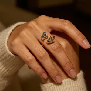 Close-up detail of double heart gold ring paved with colorful cubic zirconia on finger.