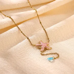 Close-up detail of the gold-plated necklace featuring a pink enamel starfish pendant.