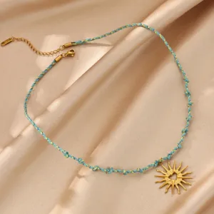 Close-up of a charming sun heart pendant necklace with blue braided cord and gold metal.