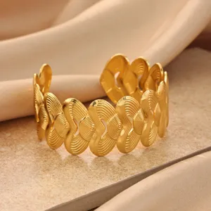 Detailed view of the gold-colored open cuff bracelet with unique swirl textured geometric design.