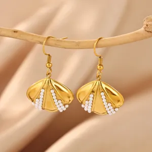 Close-up of gold shell-shaped earrings with delicate white pearl inlay, elegant detail view.