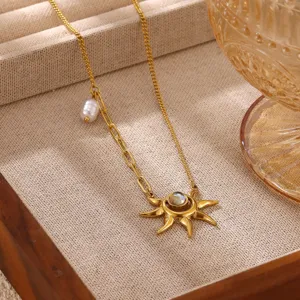 Close-up detail of the 18k gold sun pendant necklace with pearl accent on a chic beige tray.
