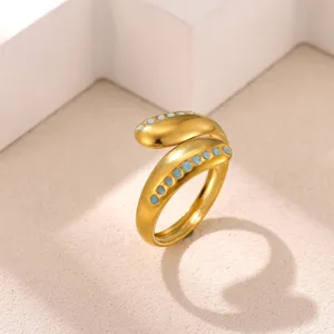 Detailed close-up of a trendy gold open geometric ring featuring vibrant blue enamel dots.