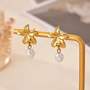 Close-up detail of gold flower earrings with pearl pendant, elegant metal jewelry display.