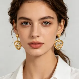 Close-up detail view of gold heart earrings with zircon and Mama lettering on model.