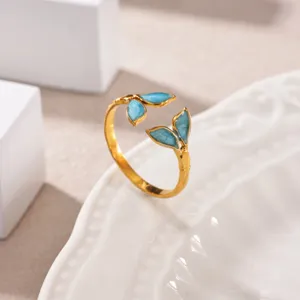 Close-up detail shot of the elegant gold-plated open ring featuring blue enamel leaf accents.